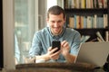 Happy man using phone and laptop in a coffee shop Royalty Free Stock Photo