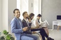 Happy man using tablet computer while waiting in line with other business people Royalty Free Stock Photo