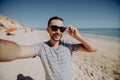 Happy man in sunglasses on vacation laughing at the beach taking selfie Royalty Free Stock Photo