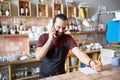 Happy man or waiter at bar calling on smartphone