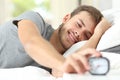 Happy man waking up turning off alarm clock Royalty Free Stock Photo