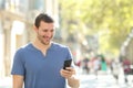 Happy man walking using mobile phone in the street Royalty Free Stock Photo