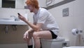 Happy Man Watching on Smartphone, Sitting in Toilet Commode