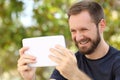 Happy man watching videos in a ereader tablet Royalty Free Stock Photo
