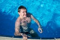 Happy man in water near swimming-pool nosing