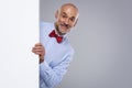 Happy man wearing bow tie while looking out of white board while standing at isolated background Royalty Free Stock Photo