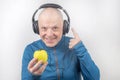 Happy man wearing portable full-size headphones listens to music using an apple player Royalty Free Stock Photo