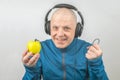 Happy man wearing portable full-size headphones listens to music using an apple player Royalty Free Stock Photo