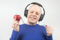 Happy man wearing portable full-size headphones listens to music using an apple player Royalty Free Stock Photo