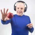 Happy man wearing portable full-size headphones listens to music using an apple player Royalty Free Stock Photo