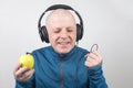 Happy man wearing portable full-size headphones listens to music using an apple player Royalty Free Stock Photo