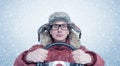 Happy man in winter clothes with a steering wheel, snow blizzard. Concept car driver Royalty Free Stock Photo