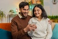 Happy man and woman couple sitting on sofa and swipe using smartphone spend time relaxing at home Royalty Free Stock Photo