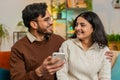 Happy man and woman couple sitting on sofa and swipe using smartphone spend time relaxing at home Royalty Free Stock Photo