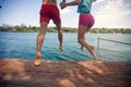 Man and woman jumping from a pier into the water
