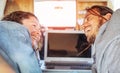 Happy man and woman looking each other and using their computer in caravan - Travel couple tender moment during their journey Royalty Free Stock Photo