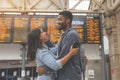 Happy man and woman in love meet and cuddle at train station in front of the timetable toned image Royalty Free Stock Photo