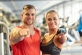 Happy man and woman pointing finger to you in gym