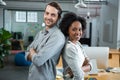 Happy man and woman standing back to back in office