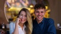 Happy man and a woman waving to the camera and laughing. Smiling couple sitting in cafe while having dating. Love Royalty Free Stock Photo