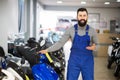 happy man worker displaying various motorcycles in workshop Royalty Free Stock Photo