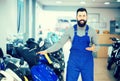 Happy man worker displaying various motorcycles in workshop Royalty Free Stock Photo