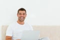 Happy man working on his laptop in his bedroom Royalty Free Stock Photo