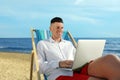 Happy man working with laptop on beach. Business trip Royalty Free Stock Photo