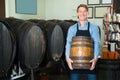 happy man working in winery and holding wine wood in cellar