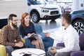 Happy marriage buying new car while talking with seller in a dea