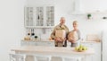 Happy married couple coming home from shopping and unpacking paper bags with groceries in kitchen together Royalty Free Stock Photo