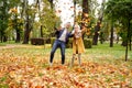 Happy married Couple having fun together outdoor in the golden autumn park, throwing leaves and laughing. Wife and husband in love Royalty Free Stock Photo
