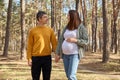 Happy married couple husband and his pregnant wife walking in spring forest holding hands looking at each other with love enjoying Royalty Free Stock Photo