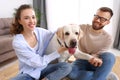 Happy married couple playing with their favorite pet dog   at home Royalty Free Stock Photo