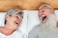 Happy married senior couple having fun lying in bed - Main focus on woman face Royalty Free Stock Photo