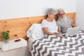 Happy married senior couple lying in bed watching videos on laptop - Mature people having fun at home - Technology elderly love Royalty Free Stock Photo