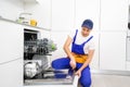 Happy master. Male technician sitting near dishwasher with screwdriver in kitchen with instruments and smiling