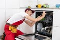 Happy master. Male technician sitting near dishwasher with screwdriver in kitchen with instruments and smiling