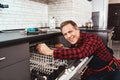 Happy master. Male technician sitting near dishwasher