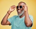 Happy mature African American man standing alone against yellow background in a studio and posing with sunglasses Royalty Free Stock Photo