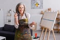 happy mature artist holding paintbrush and