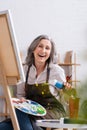 happy mature artist holding tube with