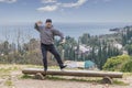 Happy mature Asian man is cheerfully dancing on the wooden bench on Mount Athos in Abkhazia