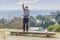 Happy mature Asian man is cheerfully dancing on the wooden bench on Mount Athos in Abkhazia