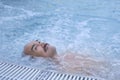 Happy mature asian man laying on water relax in outdoor thermal pool with hydromassage.