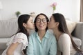 Happy mature Asian woman being kissed by her adult daughter and little granddaughter at home Royalty Free Stock Photo