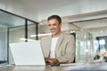 Happy mature bank manager looking at laptop in office sitting at desk. Royalty Free Stock Photo