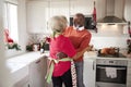 Happy mature black couple holding champagne glasses, laughing and embracing in the kitchen while preparing meal on Christmas morni Royalty Free Stock Photo