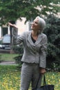 Happy mature blonde woman walks in rain and catches drops with hand, selective focus Royalty Free Stock Photo