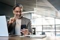 Happy mature business man sitting at office desk using mobile phone. Copy space Royalty Free Stock Photo